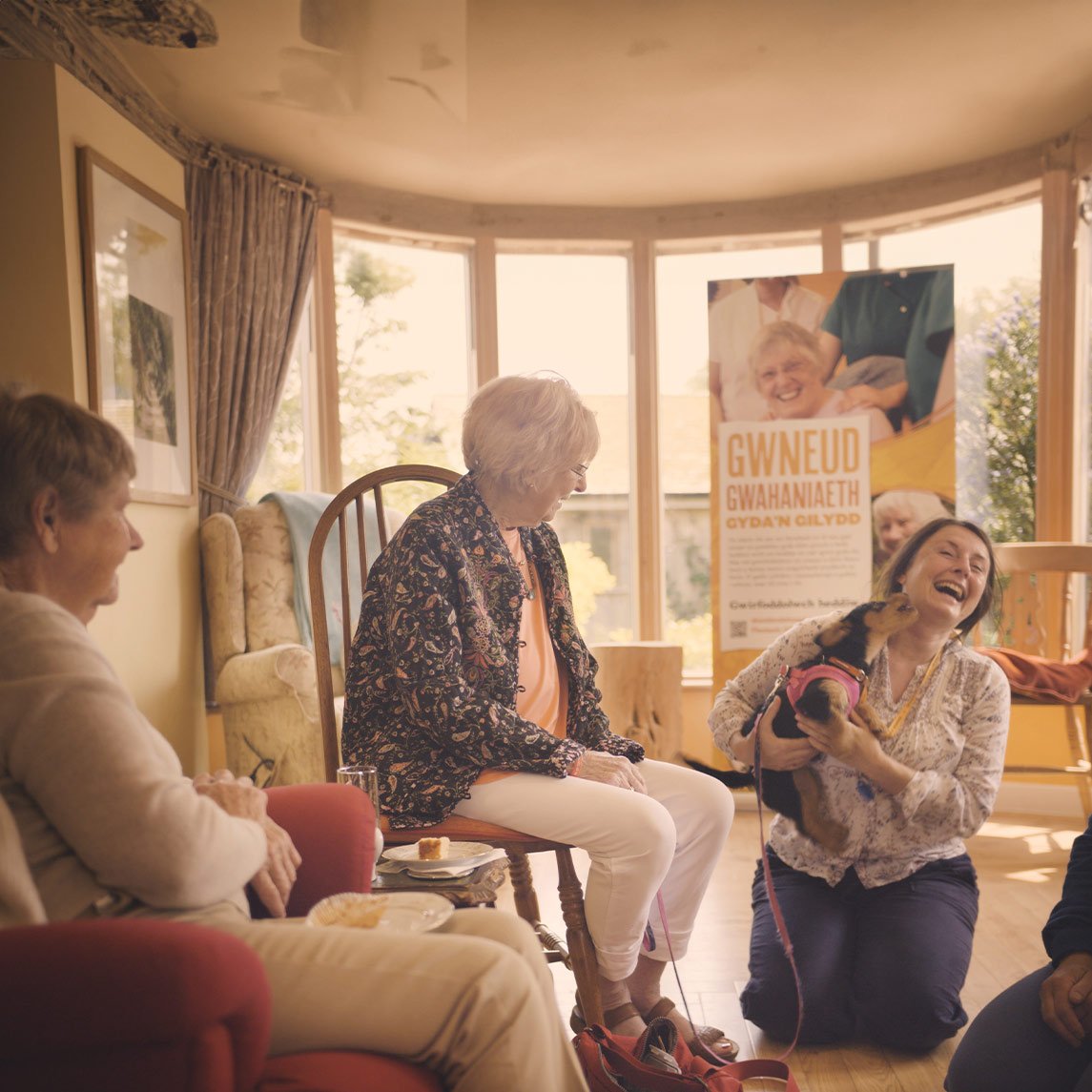 Photo of resident and volunteers playing with dog