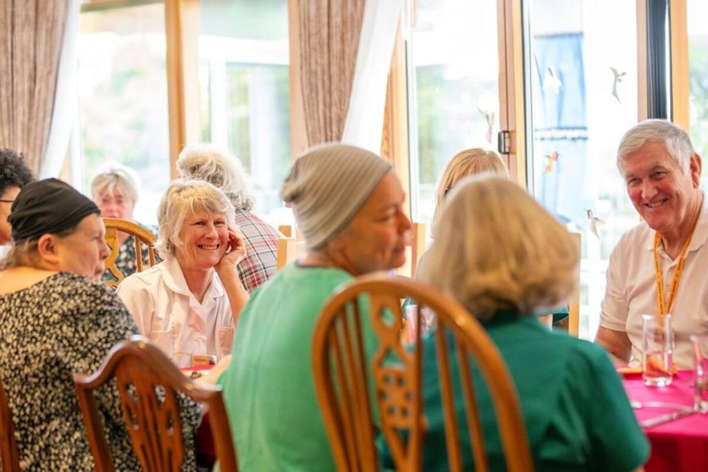 Volunteers and patients sit together for a meal at Skanda Vale Hospice.