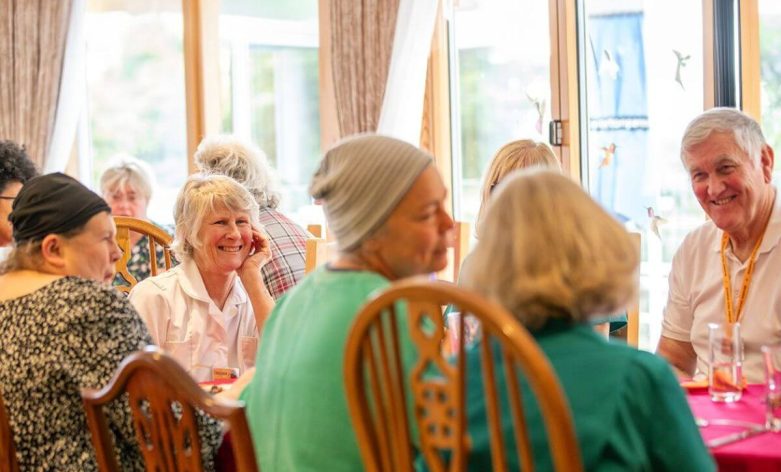 Volunteers and patients sit together for a meal at Skanda Vale Hospice.
