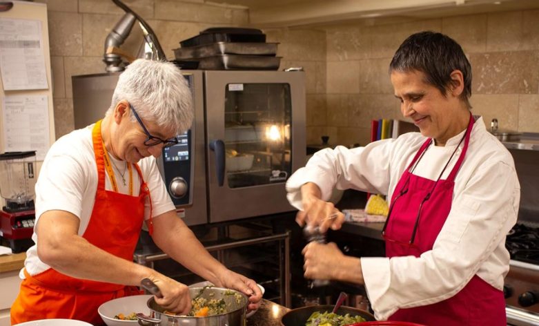 Two volunteer cooks prepare a meal in the Skanda Vale Hospice kitchen.