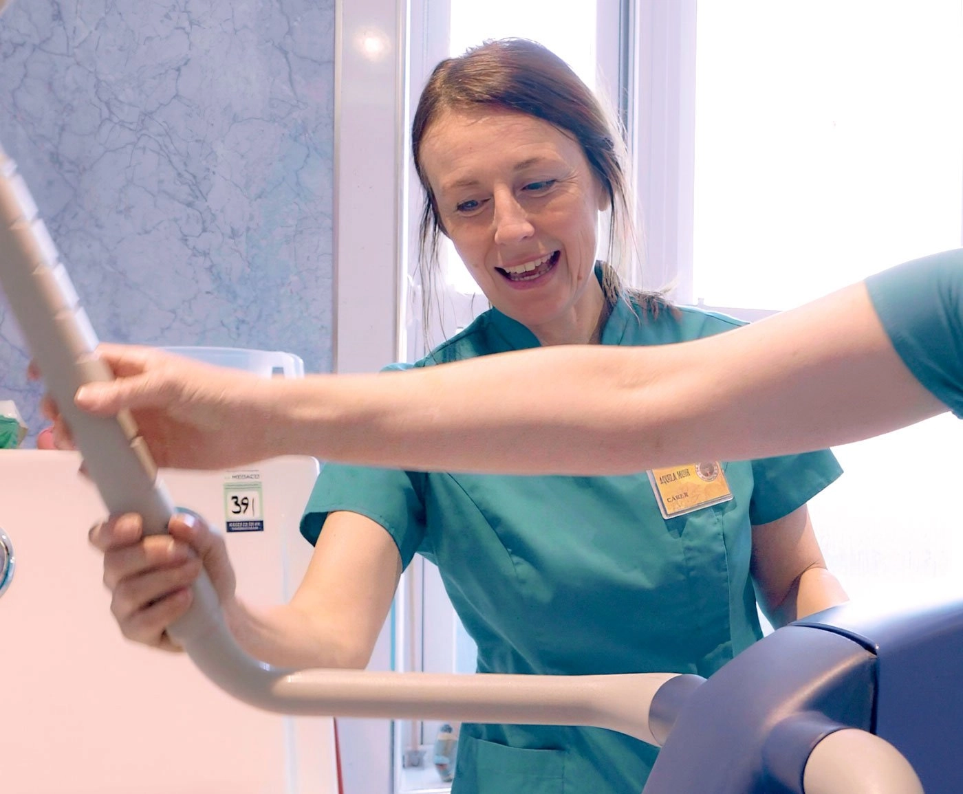 A hospice volunteer moving and handling trainer with a hoist